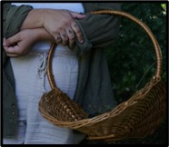 A person's hands are crossed at the waist, one hand holds a basket.