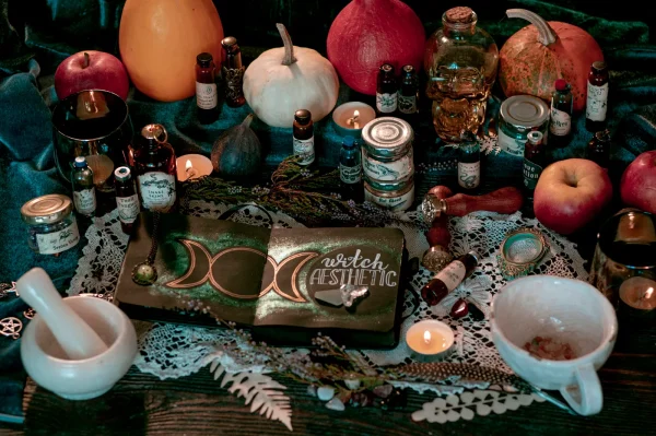 An altar with pumpkins, a mortar and pestle, various jars, and an open book that reads "witch aesthetic"